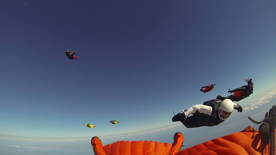 Paul Owen flying on his back in an orange wingsuit. 