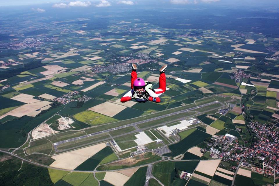 Chiara flying belly to earth with a town in the background.