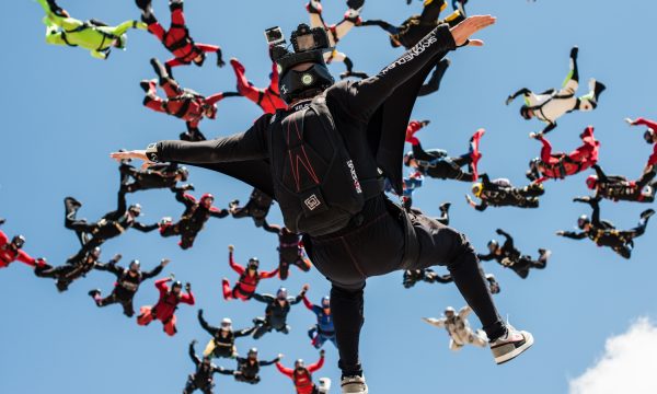 Juan flying on his back below a large formation of skydivers