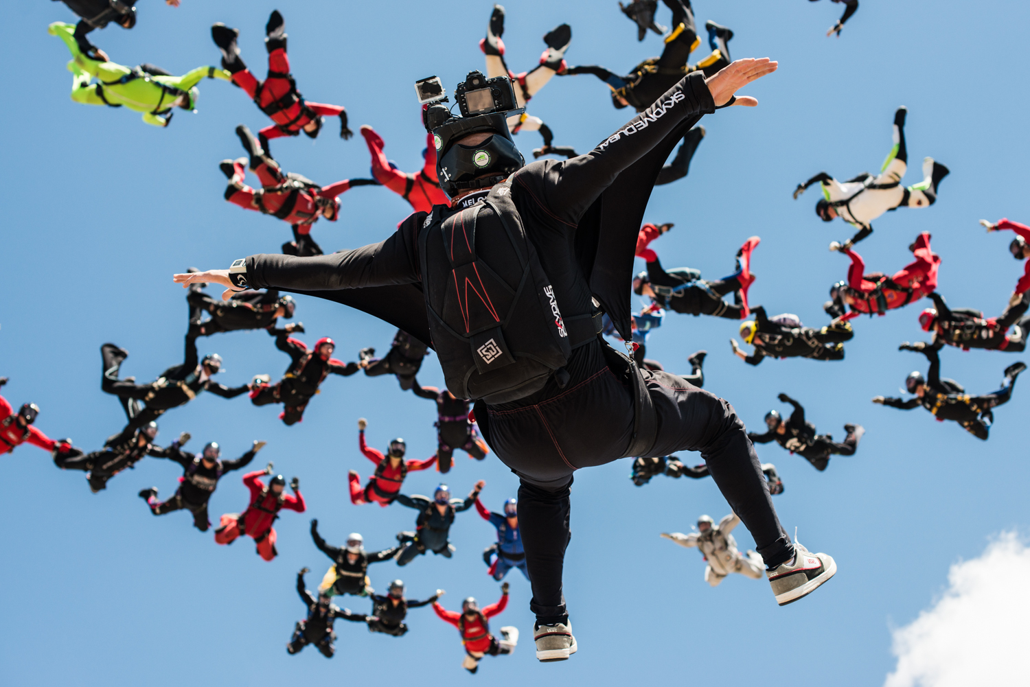 Juan flying on his back below a large formation of skydivers