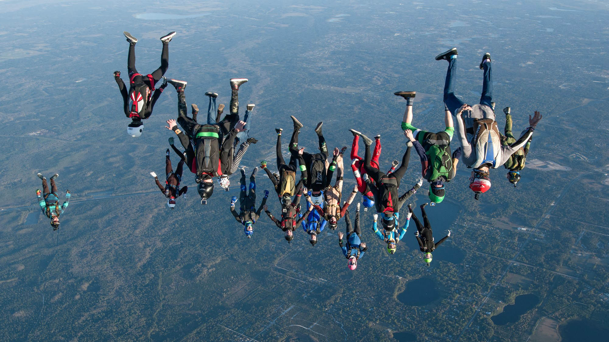 A large group of skydivers flying in a head down position.