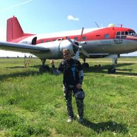 Marcus giving thumbs up in front of a red and white airplane.