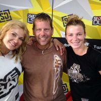 Marcus smiling with two people in front of a Skydive Dubai logoed backdrop.