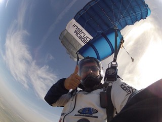 Marcus gives a thumbs up while soaring under parachute.