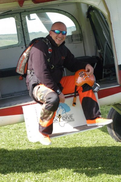 Raphael Schlegel sits on the step of an airplane while it's parked on the ground. 