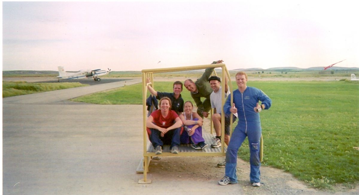 Maxine smiles with a group of others while sitting in the mockup at a DZ.