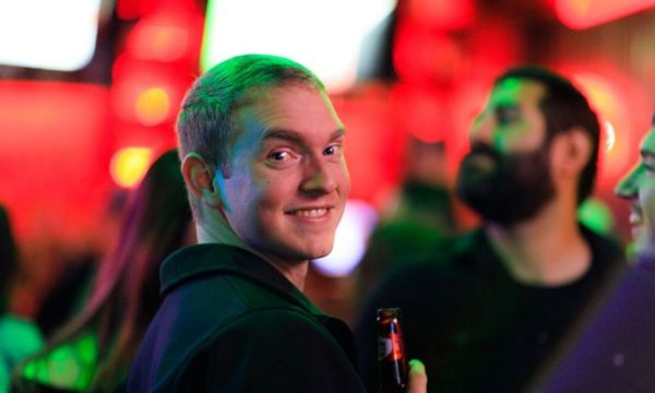 Alex Ogden smiles while drinking a beer at a dropzone party