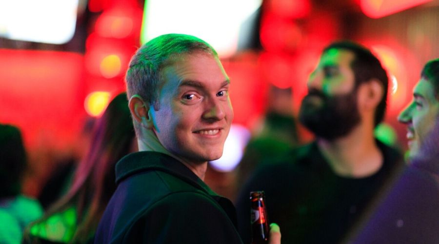 Alex Ogden smiles while drinking a beer at a dropzone party