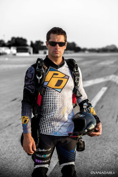 Julien smiles while standing on the runway while wearing his PD sponsored jersey