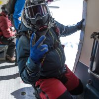Omar gives the peace sign in the aircraft before exiting above a snow covered landscape.