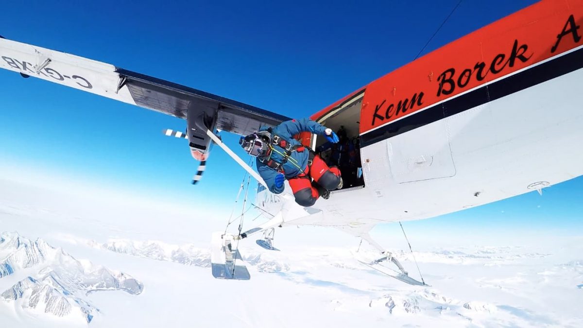 Omar exiting a Twin Otter over a snow covered landscape.