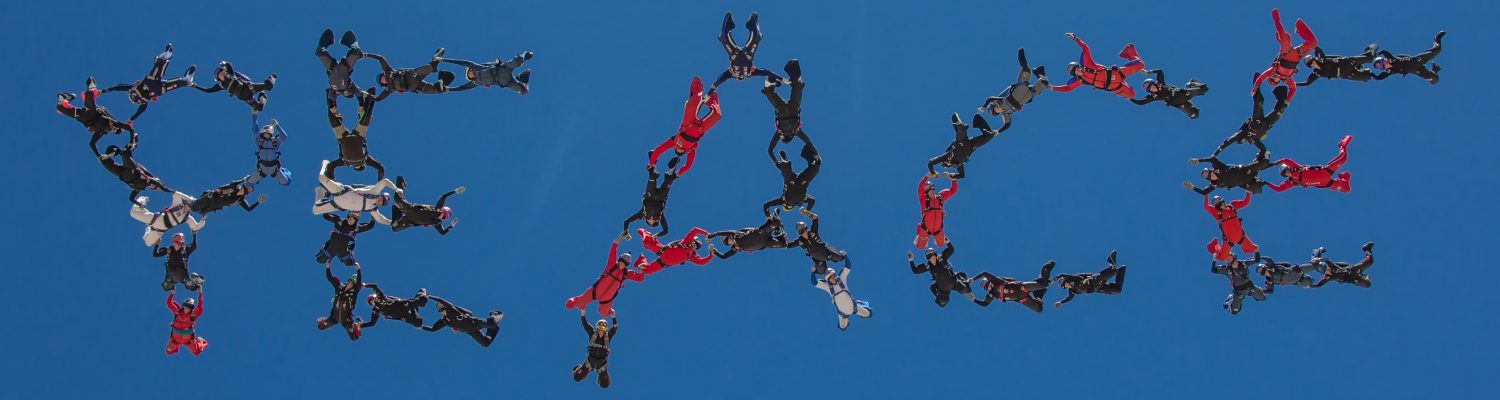 An iconic picture of a group of formation skydivers spelling the word PEACE in the sky